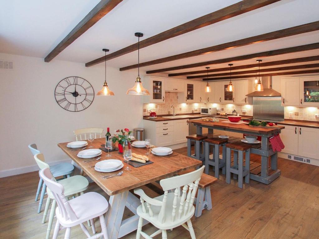 - une cuisine avec une table en bois et des chaises blanches dans l'établissement Gwyndy Bach, à Beddgelert