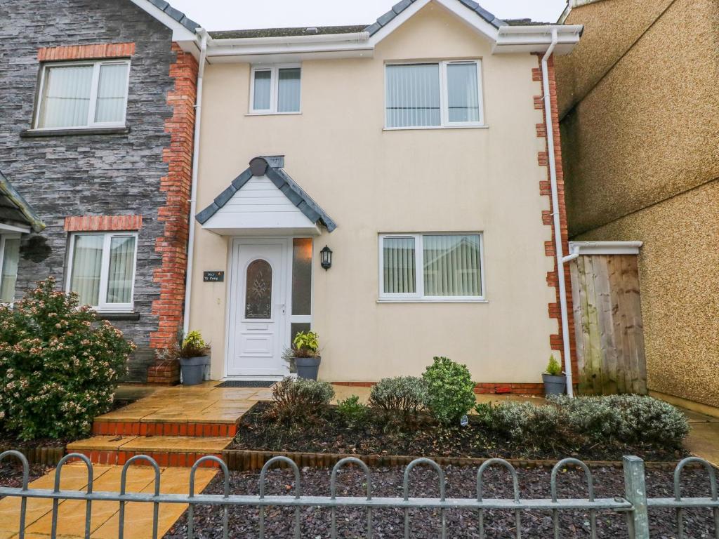 a house with a white door and a fence at Ty Cerrig in Ammanford