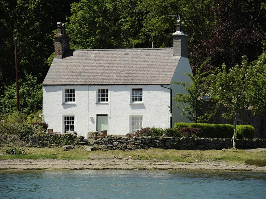 a white house sitting next to a body of water at Min Y Mor in Llanfairpwllgwyngyll