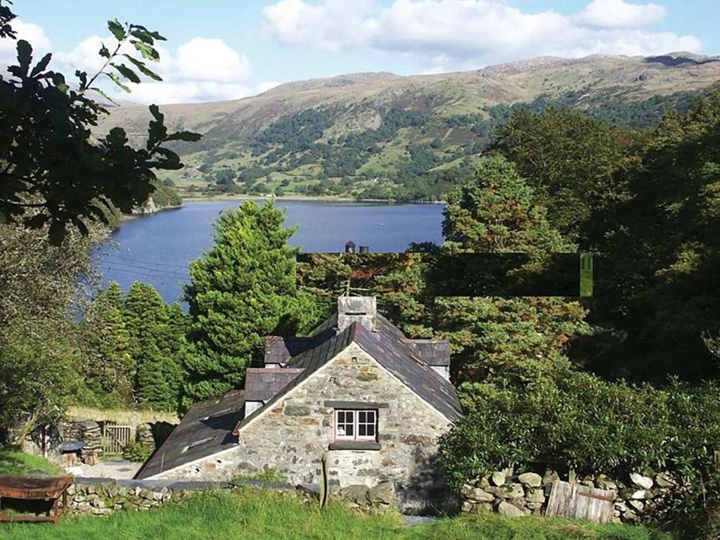 an old stone house on the side of a lake at Pantlleni in Beddgelert