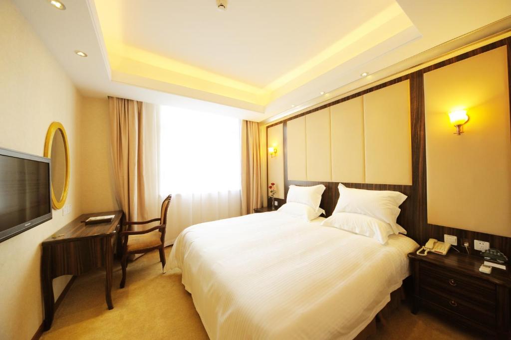 a hotel room with a large bed and a desk at Greentree Inn Shanghai West Huaxia Road Metro Station Express Hotel in Shanghai