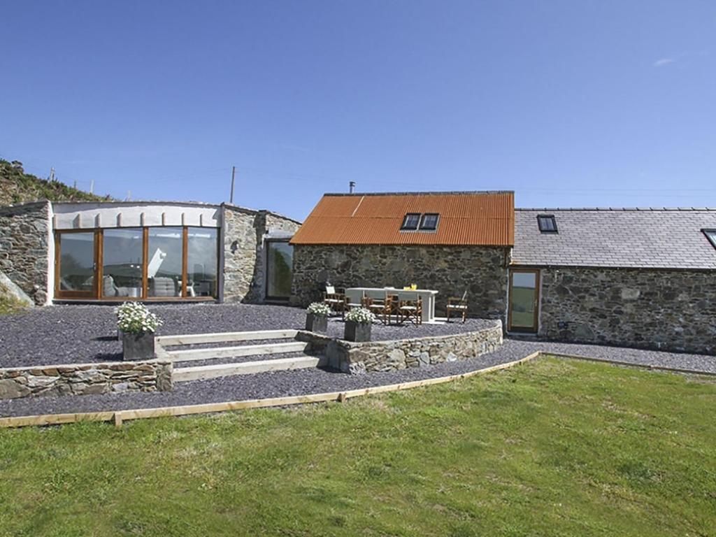 a home with a stone building with a patio at Rhyd Angharad Barns in Llanrhyddlad