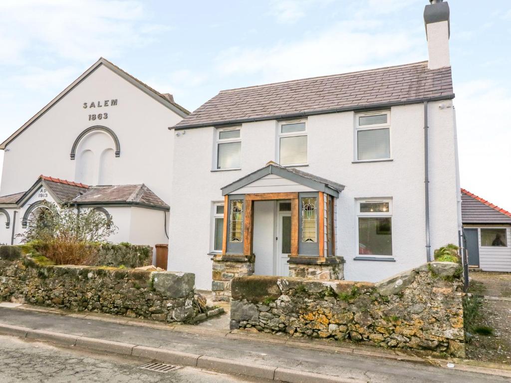 a white house with a stone wall in front of it at Ty Capel in Pwllheli