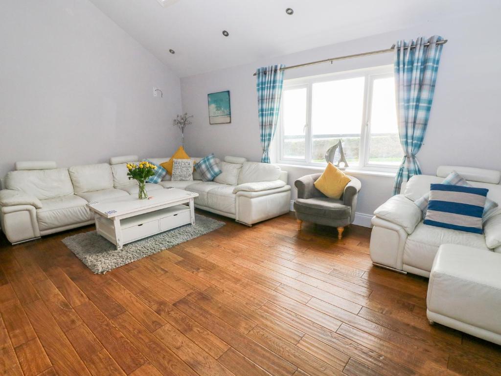 een woonkamer met witte meubels en houten vloeren bij Swn y mor in Narberth