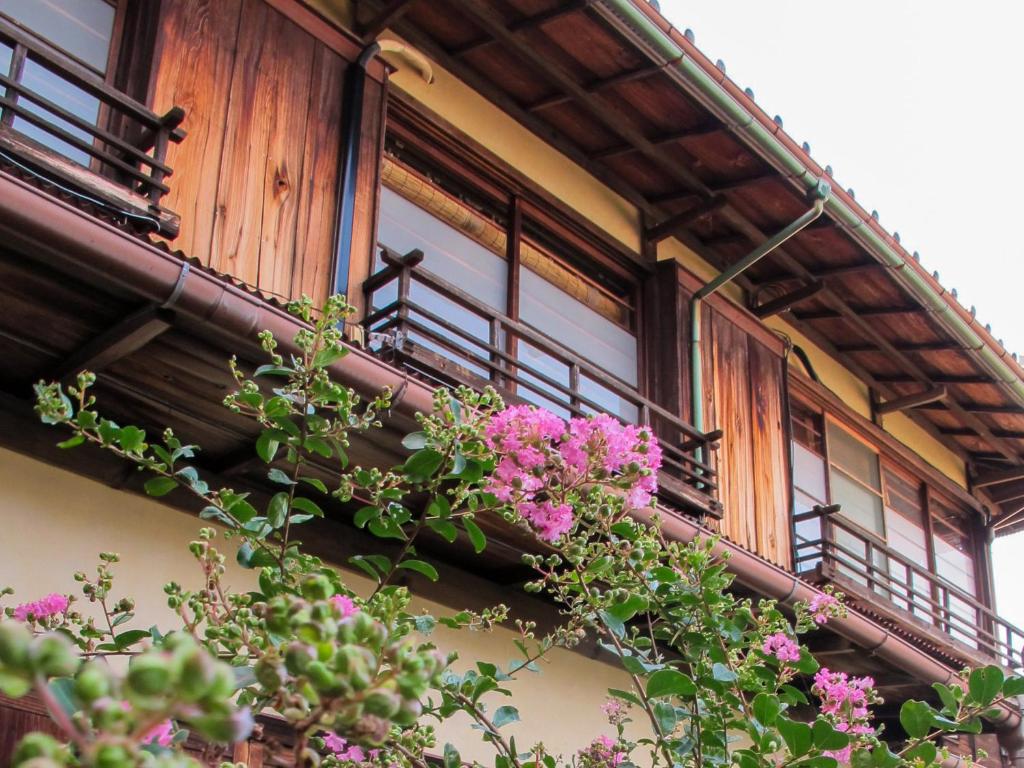 un balcón con flores rosas en un edificio en Atami Ikyuan 熱海一休庵, en Atami