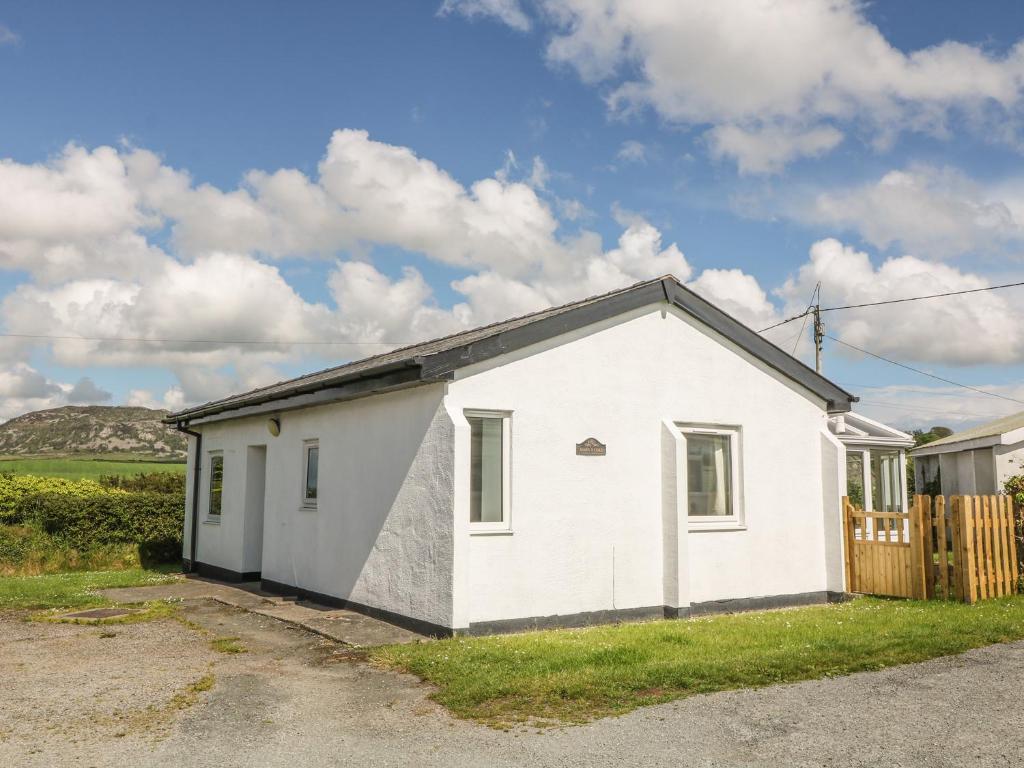 a small white house with a wooden fence at Maes Y Coed in Pwllheli