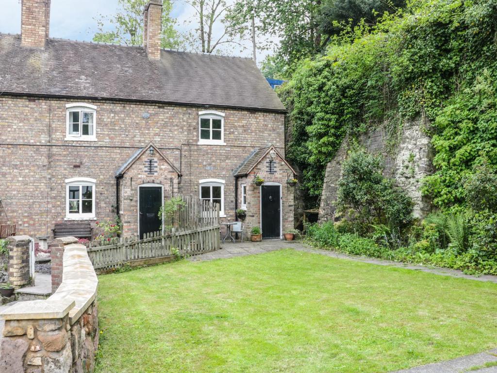 an old brick house with a yard in front of it at Bridge View Cottage in Telford