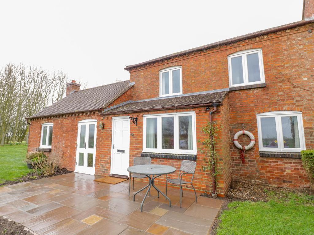 a brick house with a table and chairs in front of it at Wigrams Canalside Cottage in Southam