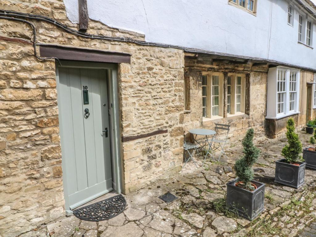 a stone cottage with a green door and potted plants at 10 George Yard in Burford