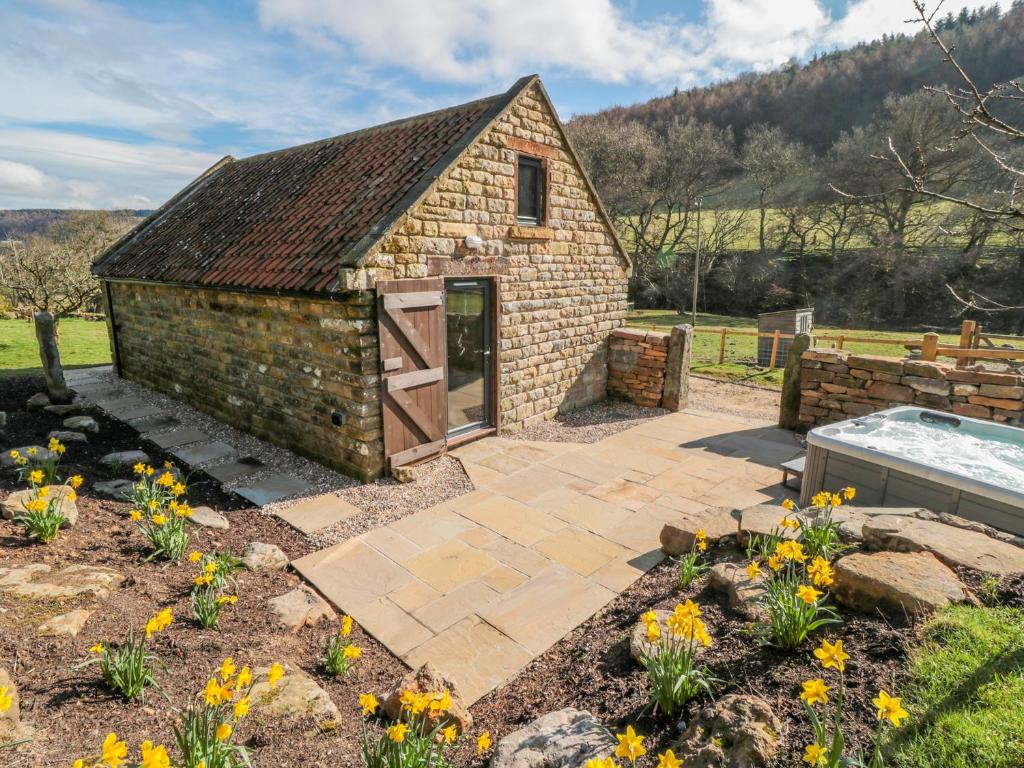 a small brick building with a patio in a garden at Thompson Rigg Barn in Scarborough