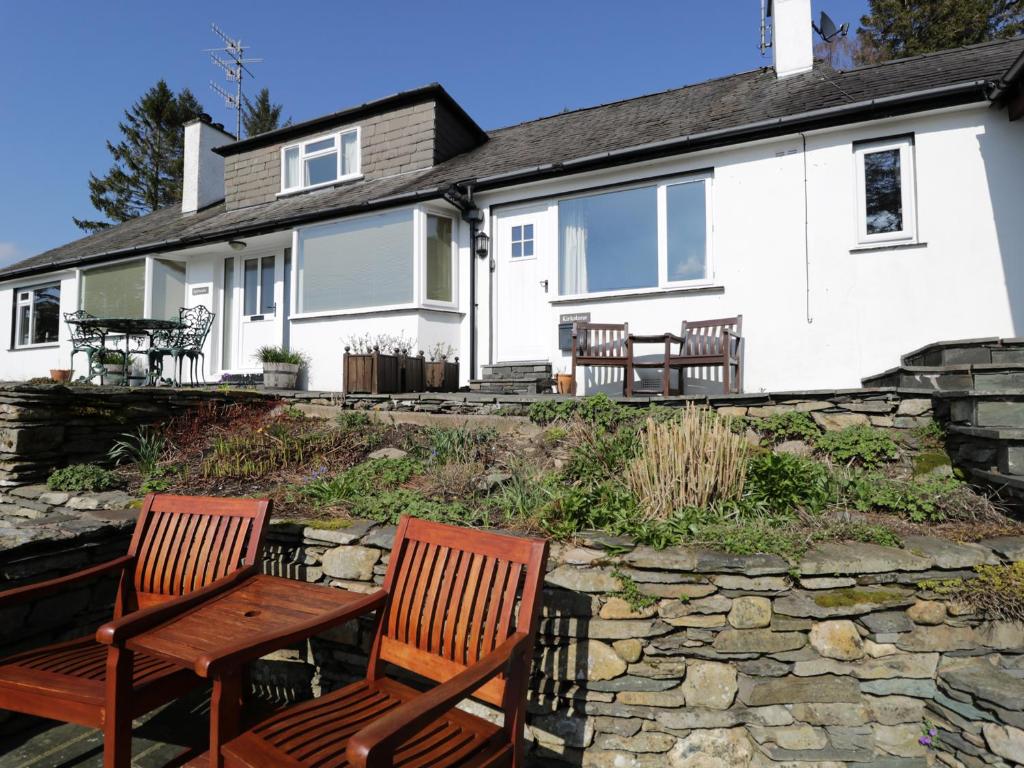 two wooden chairs in front of a white house at Kirkstone Cottage in Ambleside
