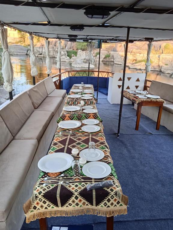 a long table on a boat with plates on it at Houseboat Hotel and Nile Cruises Zainoba in Nag` el-Ramla