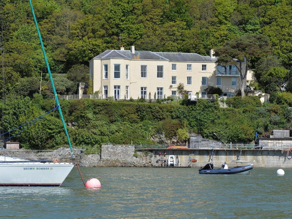 two boats in the water in front of a large house at Tan Y Coed in Menai Bridge