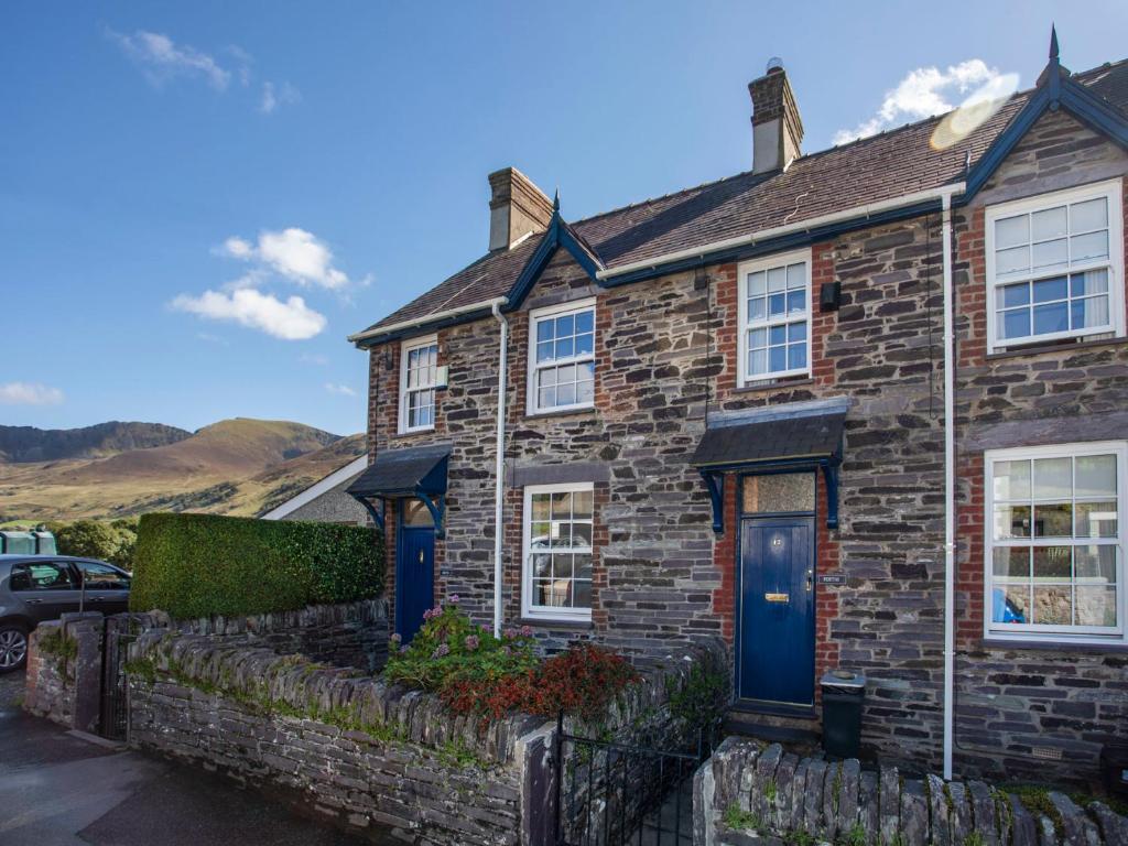 a stone house with blue doors and a fence at 17 Victoria Terrace - Perthi in Nantlle