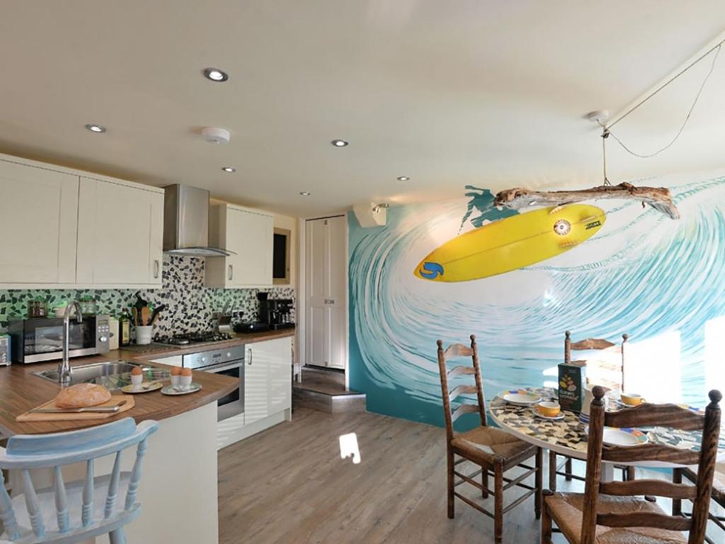 a kitchen with a painting of a surfboard on the wall at Y Stabl in Criccieth