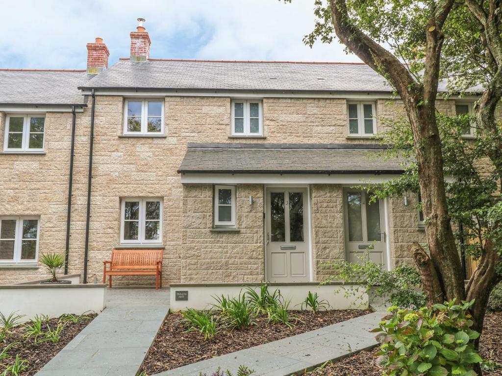 a brick house with an orange bench in front of it at Tinners Rest in Penzance