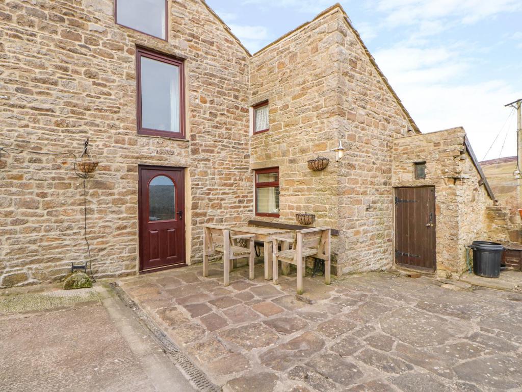 a stone house with a wooden table in the courtyard at Beckelshele in Bishop Auckland