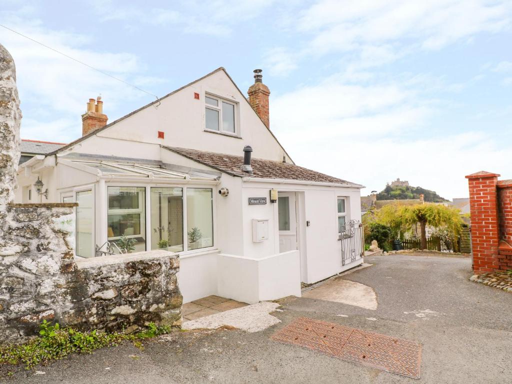 ein weißes Haus mit einer Steinmauer in der Unterkunft Mount View Cottage in Marazion