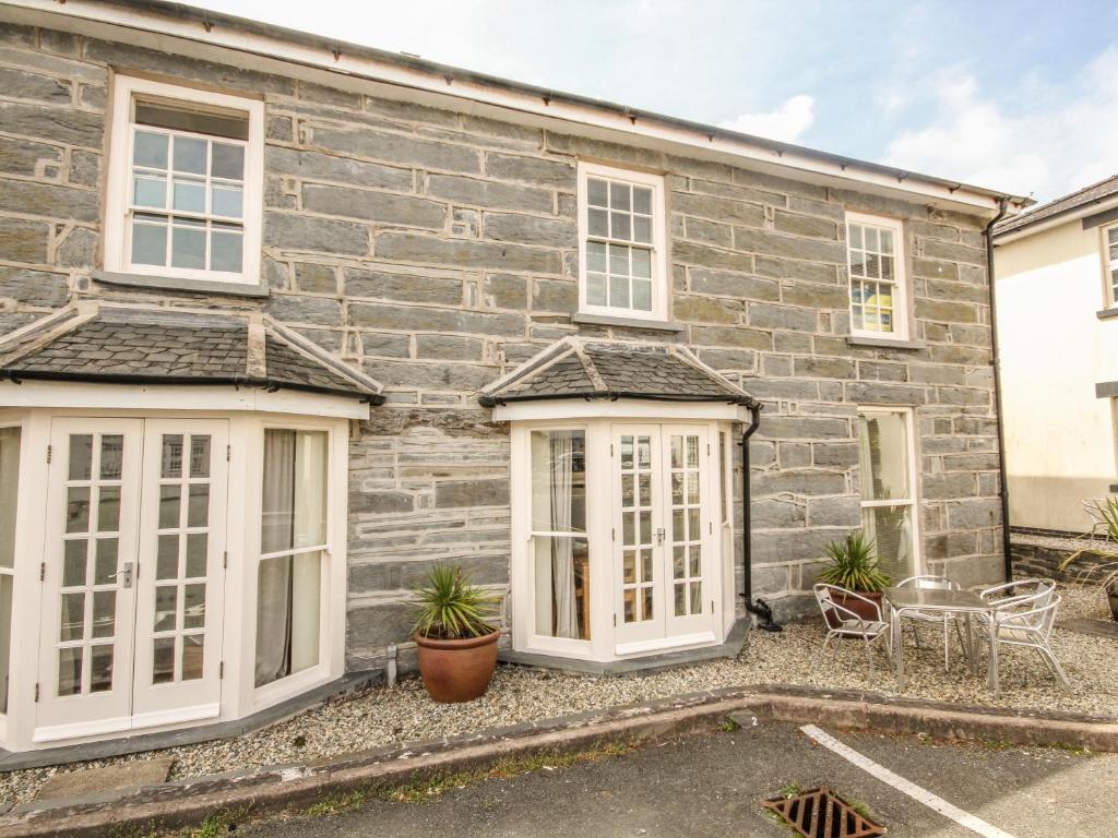 a stone house with white windows and a building at Bwthyn Llechen in Porthmadog
