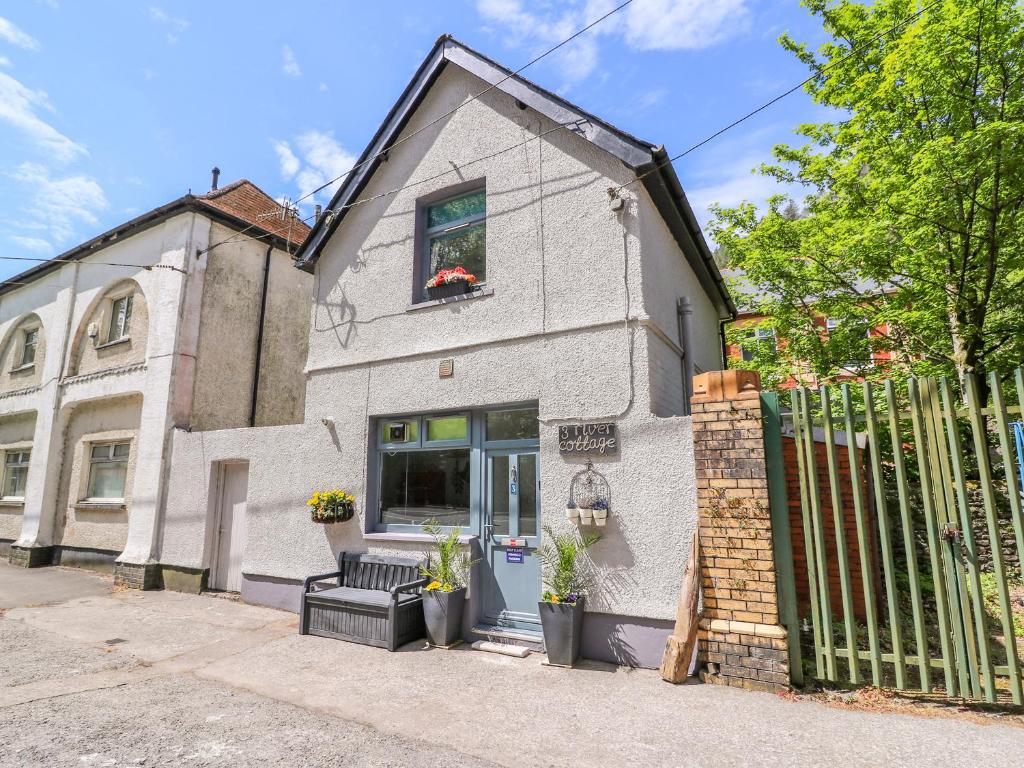 a white house with a fence in front of it at River Cottage in Port Talbot