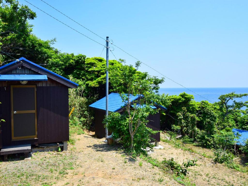 a small house with a blue roof and the ocean in the background at Tonosaki Bungalow & BBQ in Tsushima