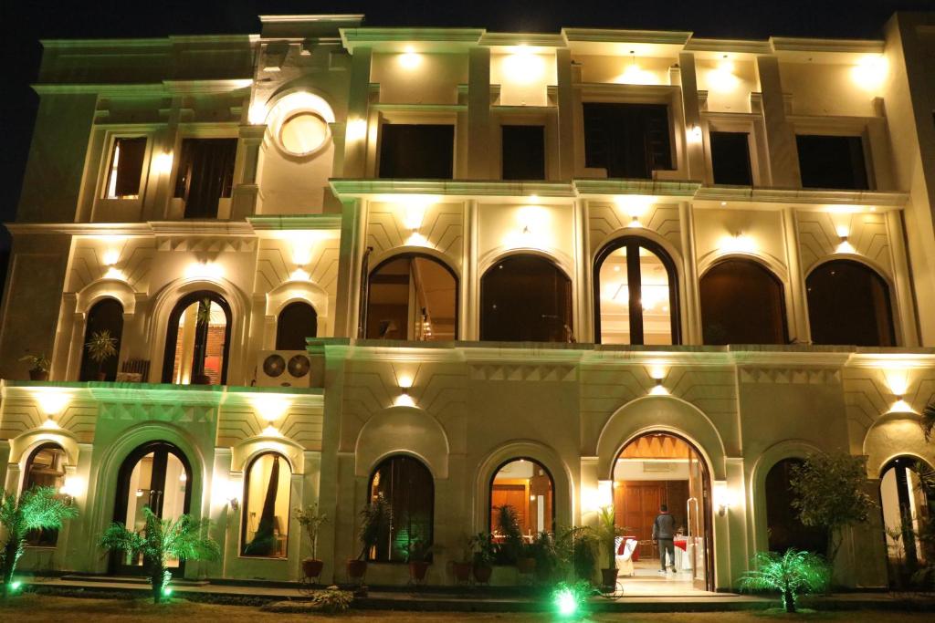 a building with a clock on the side of it at night at Hotel Pushap Palace in Patiāla