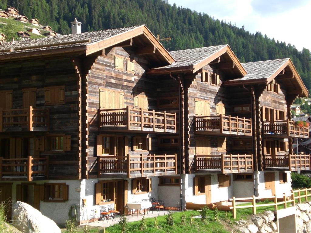 ein großes Holzgebäude mit Balkon auf einem Berg in der Unterkunft Apartments Vieux Chalet in Grimentz