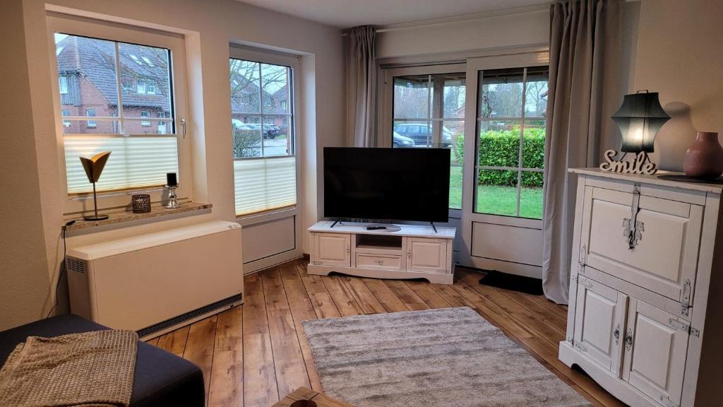 a living room with a flat screen tv and windows at Fewo Heimathafen 188 in Petersdorf auf Fehmarn