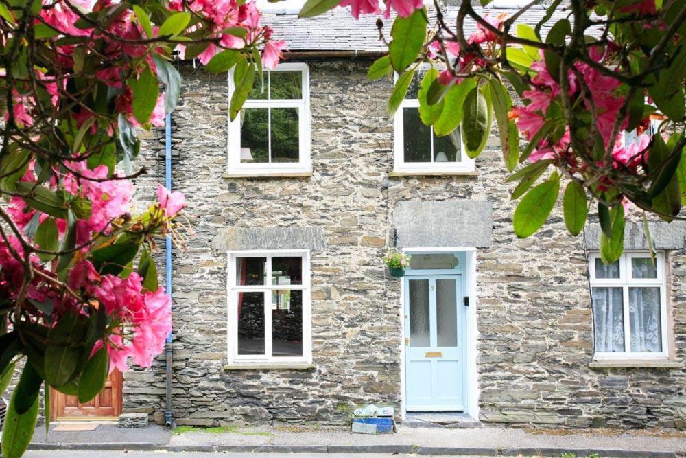 a stone house with pink flowers in front of it at Stone Cottage at Staveley in Windermere