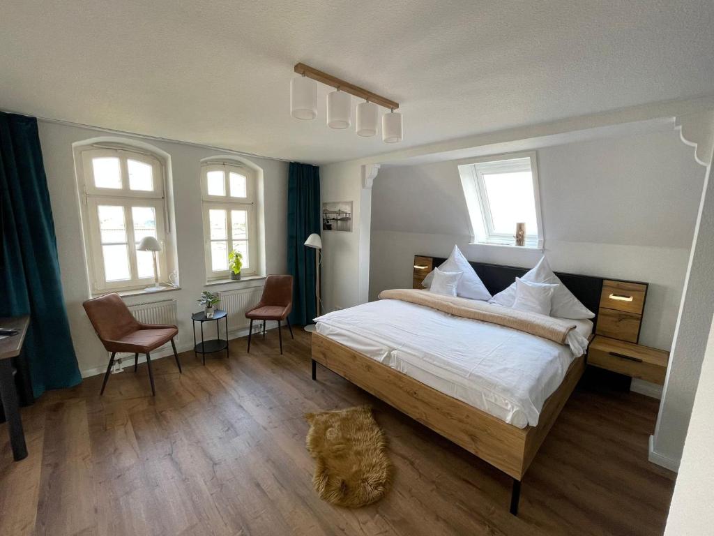 a bedroom with a bed and two chairs and windows at Kanal-Haus "Das Gästehaus direkt am NOK" in Osterrönfeld