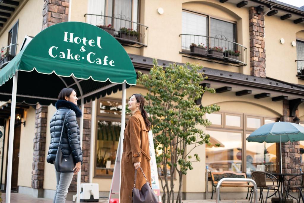 dos mujeres caminando en frente de un hotel y café de pasteles en HOTORI no HOTEL BAN, en Fujikawaguchiko