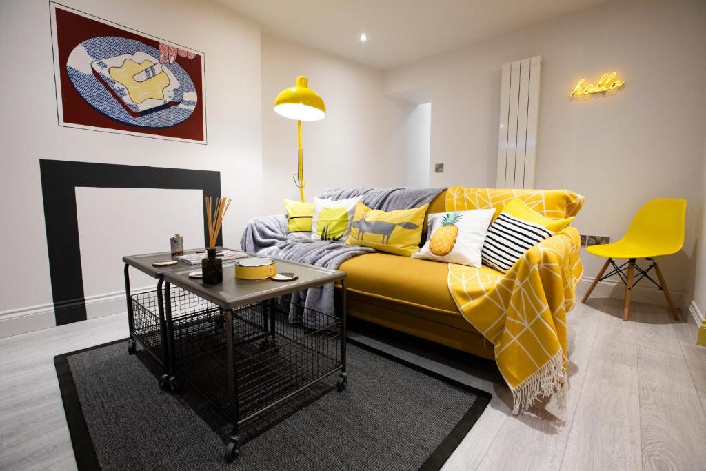 a living room with a yellow couch and a table at Nadler House 1 Bed Basement Apartment in Norwich