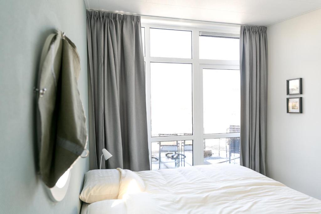 um quarto com uma cama e uma grande janela em 8p Luxe bungalow met serre em s-Gravenzande