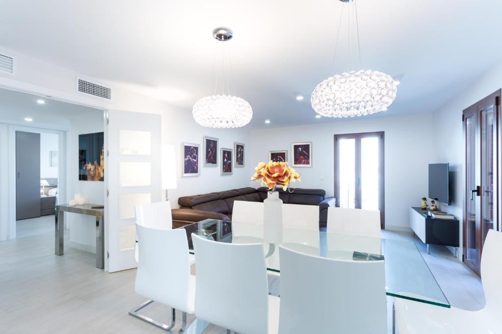 a living room with a glass table and white chairs at Rincón del Duende in Seville