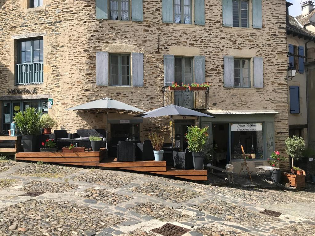 un hotel con tavoli e ombrelloni di fronte a un edificio di Chez Tifille a Estaing