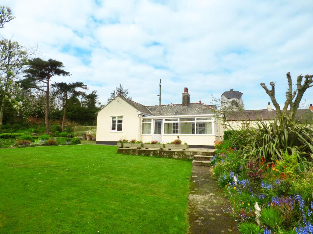a white house with a garden in front of it at Hafod Cottage in Cemaes Bay