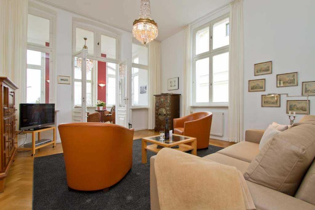 ein Wohnzimmer mit einem Sofa, Stühlen und einem TV in der Unterkunft Die Villa, App 1 in Ahlbeck