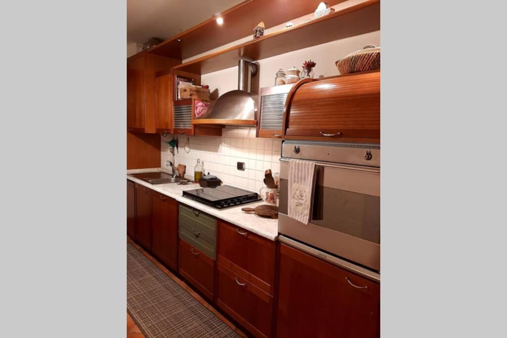 uma cozinha com armários de madeira e electrodomésticos de aço inoxidável em La casetta nel verde em Ronago