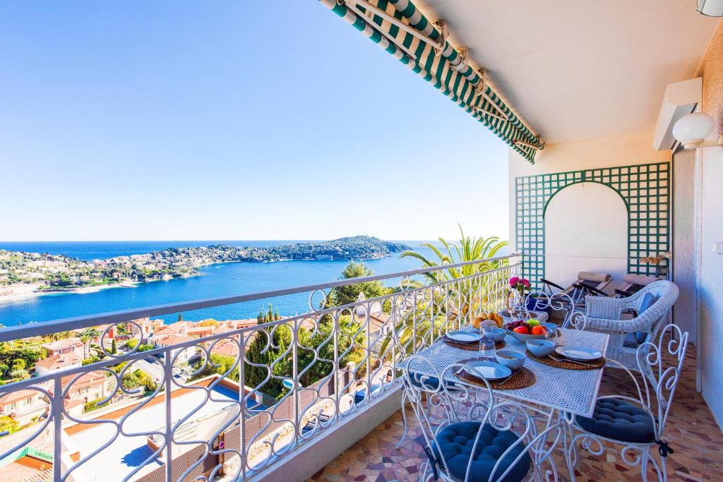 a balcony with a table and chairs and a view of the ocean at Terrace on the Bay 2 Villefranche-sur-Mer, AP4243 by Riviera Holiday Homes in Villefranche-sur-Mer