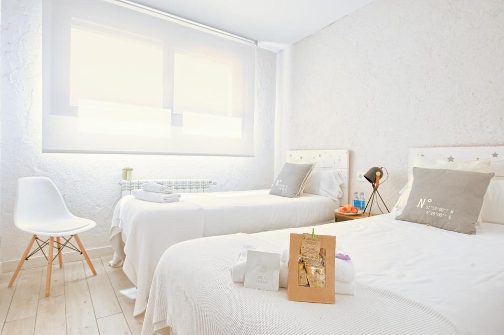 a white room with two beds and a chair at Albergue LaMorena in Ledigos