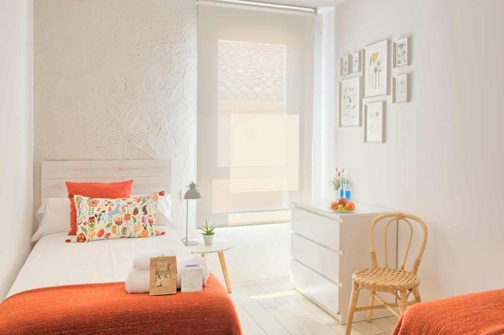 a white bedroom with a bed and a chair at Albergue LaMorena in Ledigos