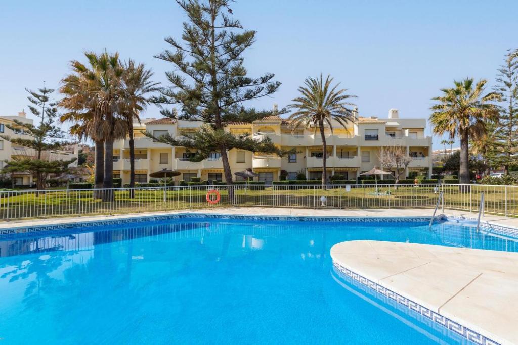 a large swimming pool with palm trees and condos at Beach apartment La Cala in La Cala de Mijas