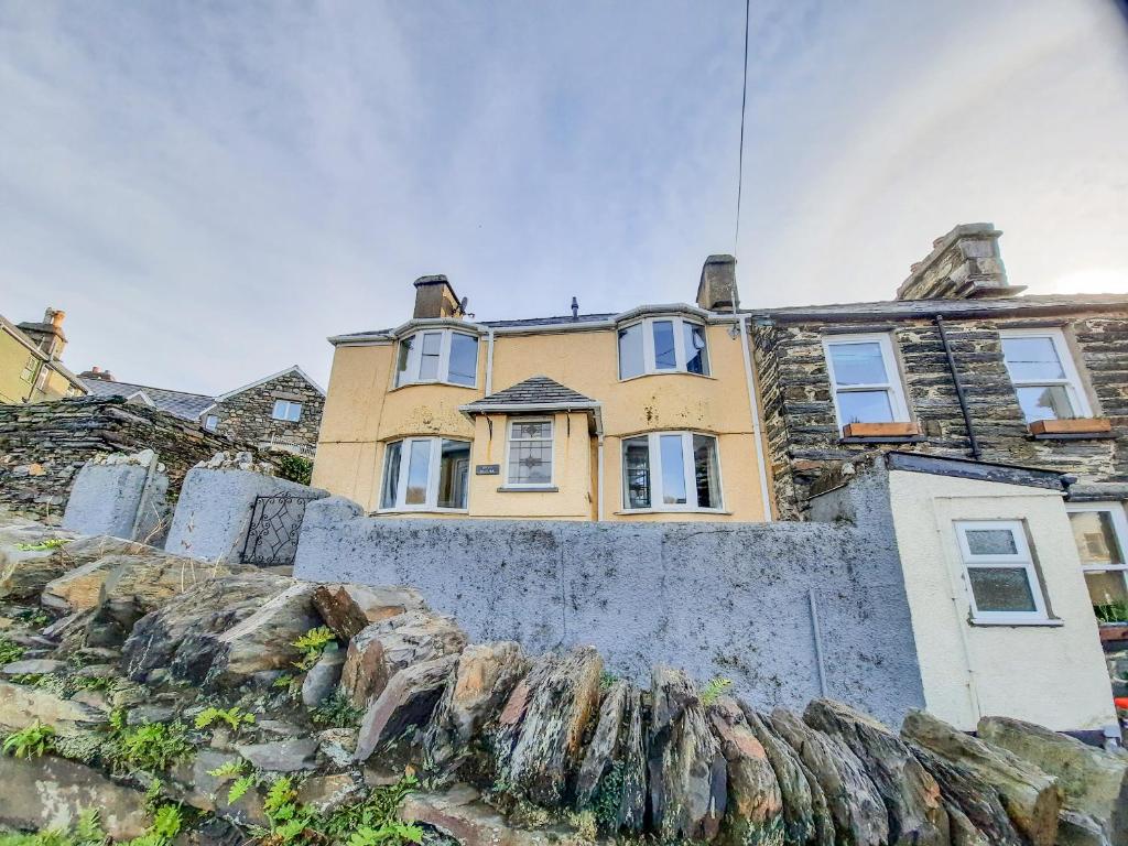 una casa amarilla en la parte superior de una pared de piedra en Bryn Bethel, en Penrhyndeudreath