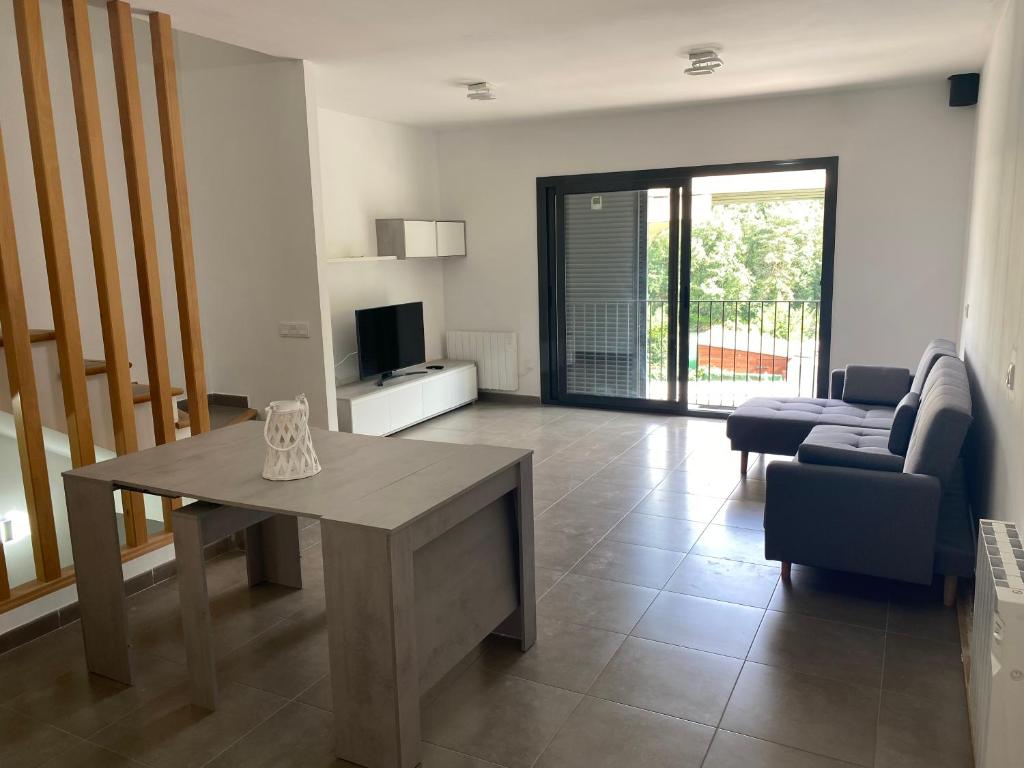 sala de estar con mesa y sofá en Ample house w/ Views in front of Baells reservoir, en Sant Jordi de Cercs