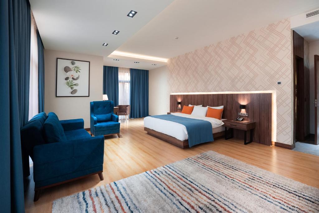 WELLNESS HOTEL and SPA في طشقند: غرفه فندقيه بسرير وكرسي ازرق