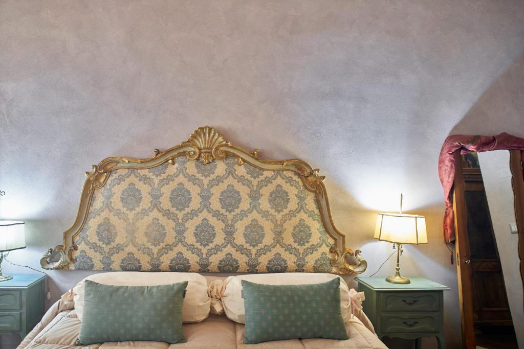 ein Bett mit verziertem Kopfteil und zwei Nachttischen in der Unterkunft Alla Scala 1746 in Siena