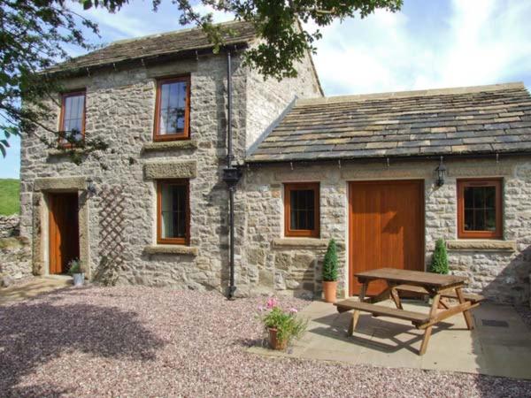 a stone house with a picnic table in front of it at Swallows Barn in Buxton