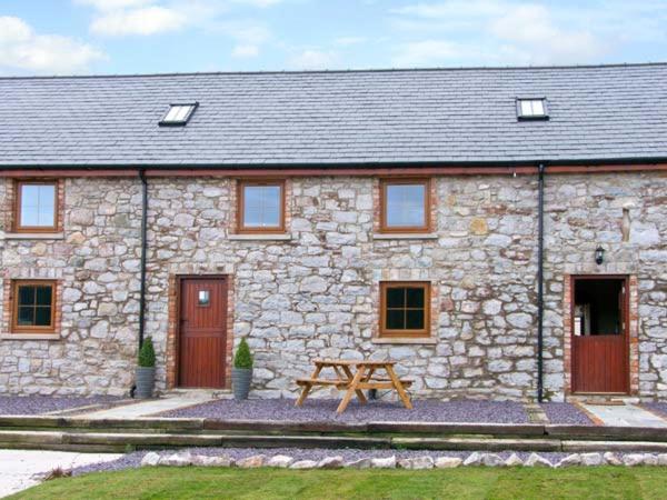 una casa de piedra con una mesa de picnic delante de ella en Beudy Bach en Abergele