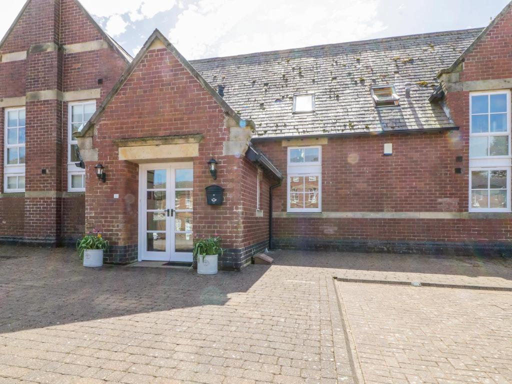 a brick building with a white door and two potted plants at Carpenters Cottage in Cockermouth