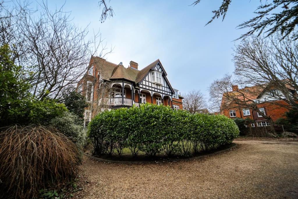 une grande maison avec un grand bush devant elle dans l'établissement Tudor Villas Apartment, Cromer, à Cromer